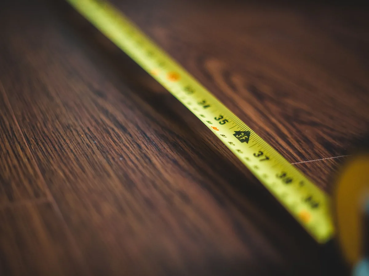 Cinta métrica extendida sobre un suelo de madera para calcular superficies